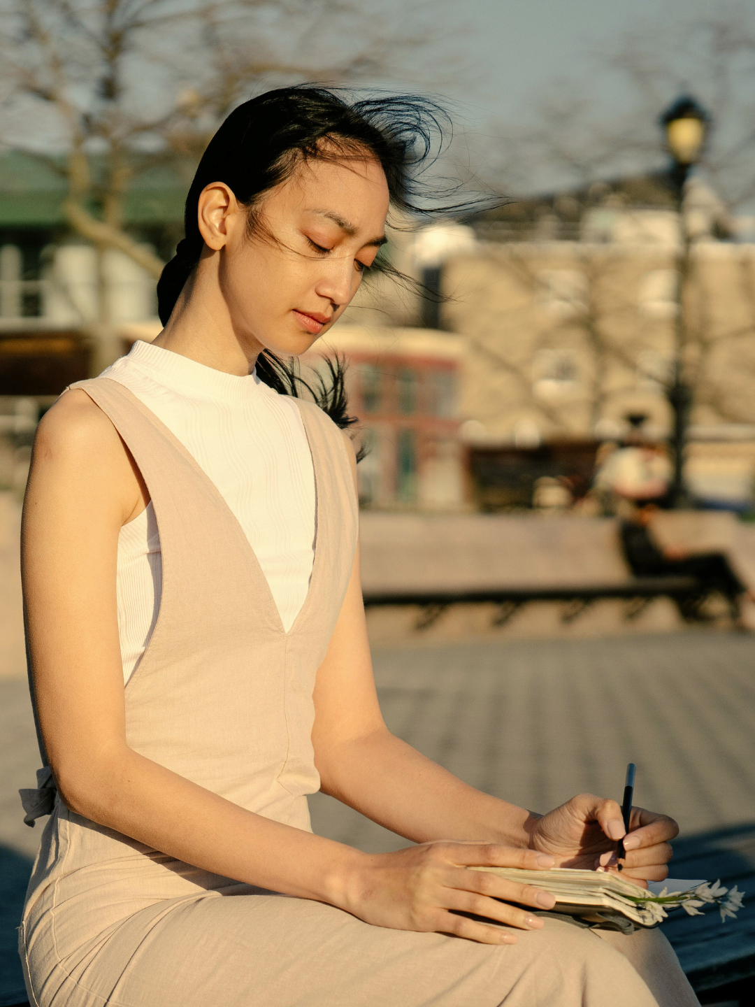 Person journaling outdoors in warm sunlight — contemplative moment of reflection